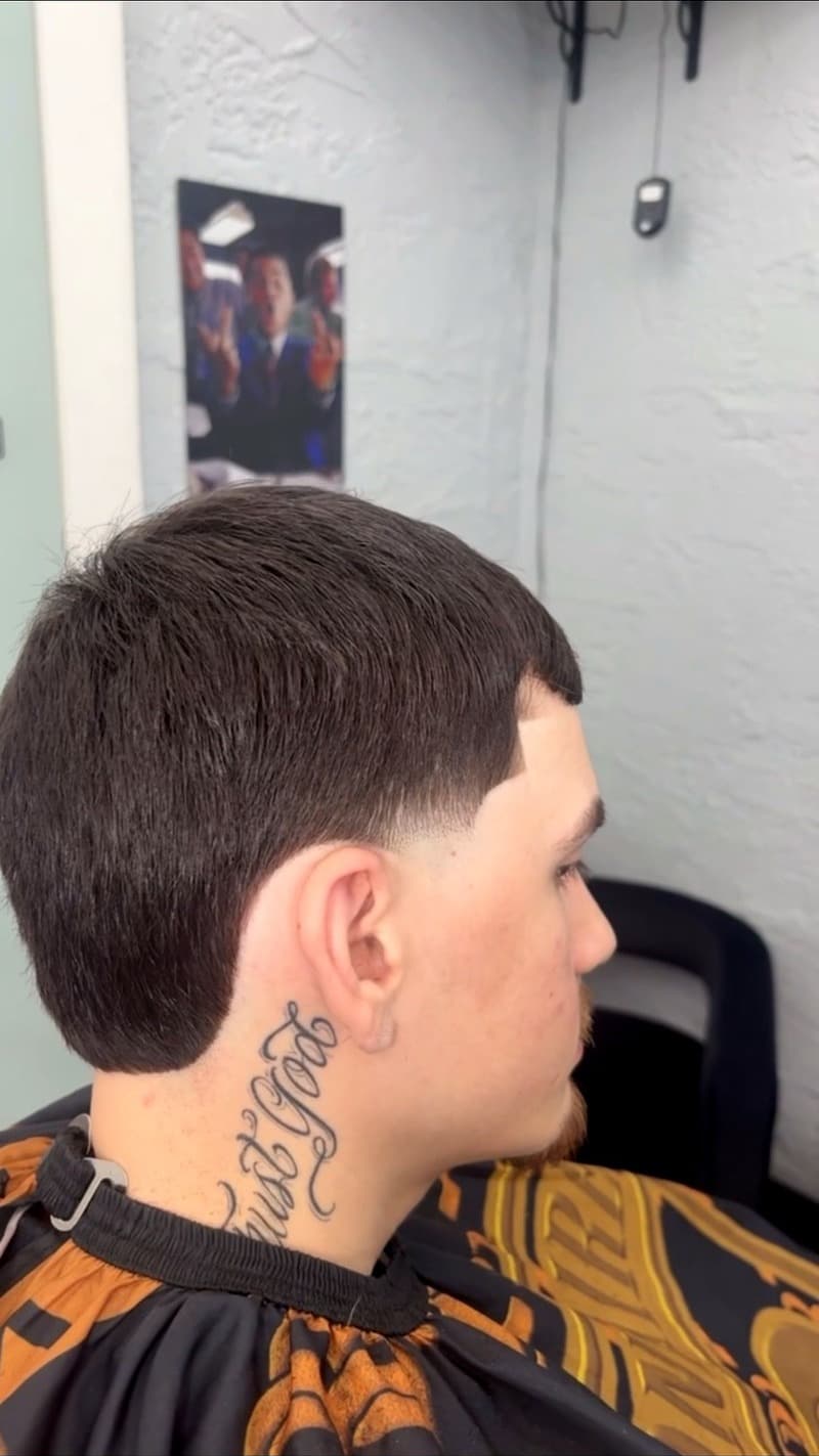 Taper fade side profile with neck tattoo — clean blend