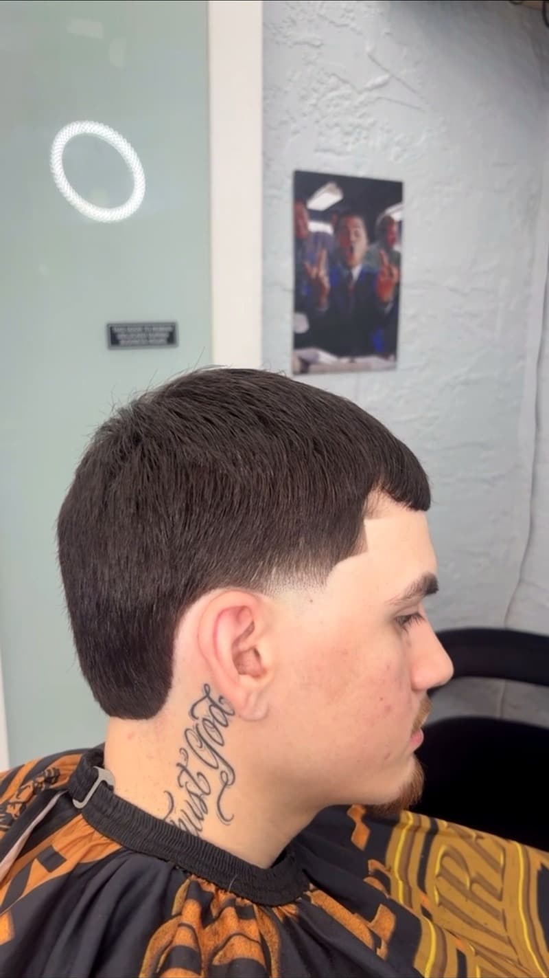 Low fade side profile with neck tattoo — ring light in background