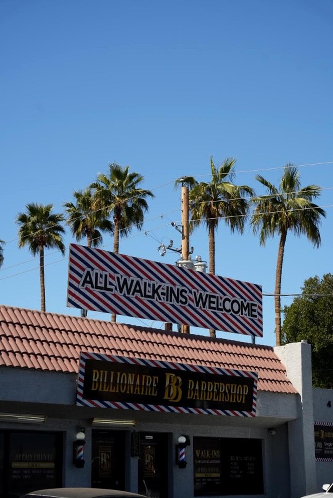 Billionaire Barbershop storefront — ALL WALK-INS WELCOME sign with palm trees